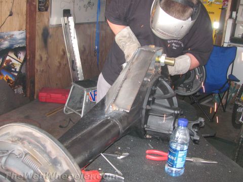 1968 Ford Mustang - A person in a welding mask and gloves works on a rear axle assembly, sparks flying.