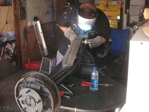 1968 Ford Mustang - A person is welding a car's rear axle assembly, which includes drum brakes and suspension components.