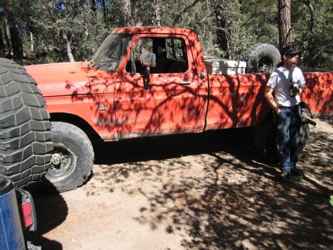 1974 Ford F-250 - Orange pickup truck with large tires and a man standing next to it in a wooded area.