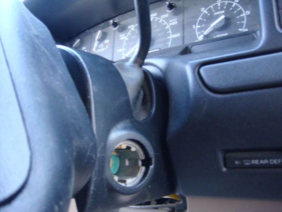 Vehicle interior with ignition cylinder and dashboard gauges. Rear Def button visible