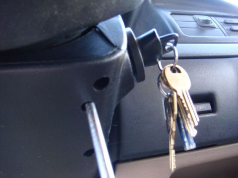 1996 Ford Bronco - Ignition cylinder with keys and a screwdriver inserted nearby.