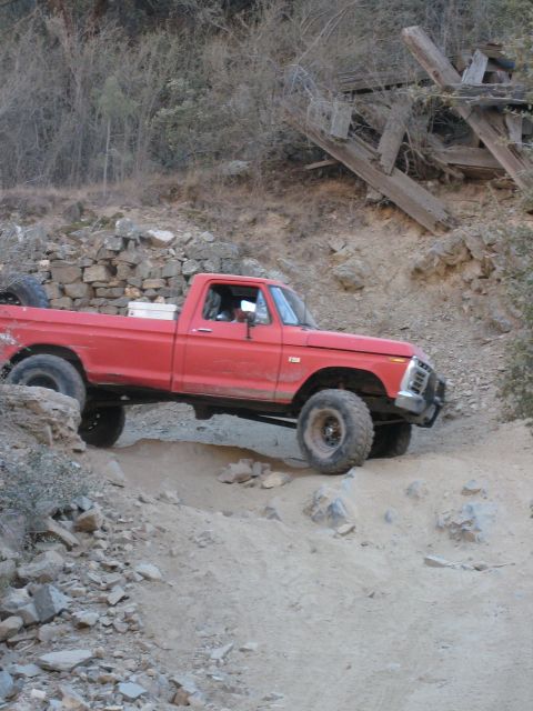1974 Ford F-250 - A red pickup truck navigates a rocky, off-road trail.