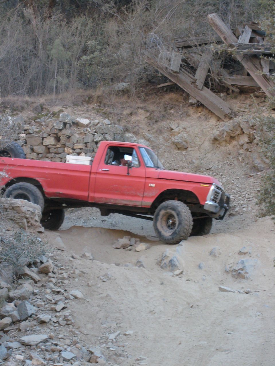 Red pickup truck on a dirt trail, front grille visible