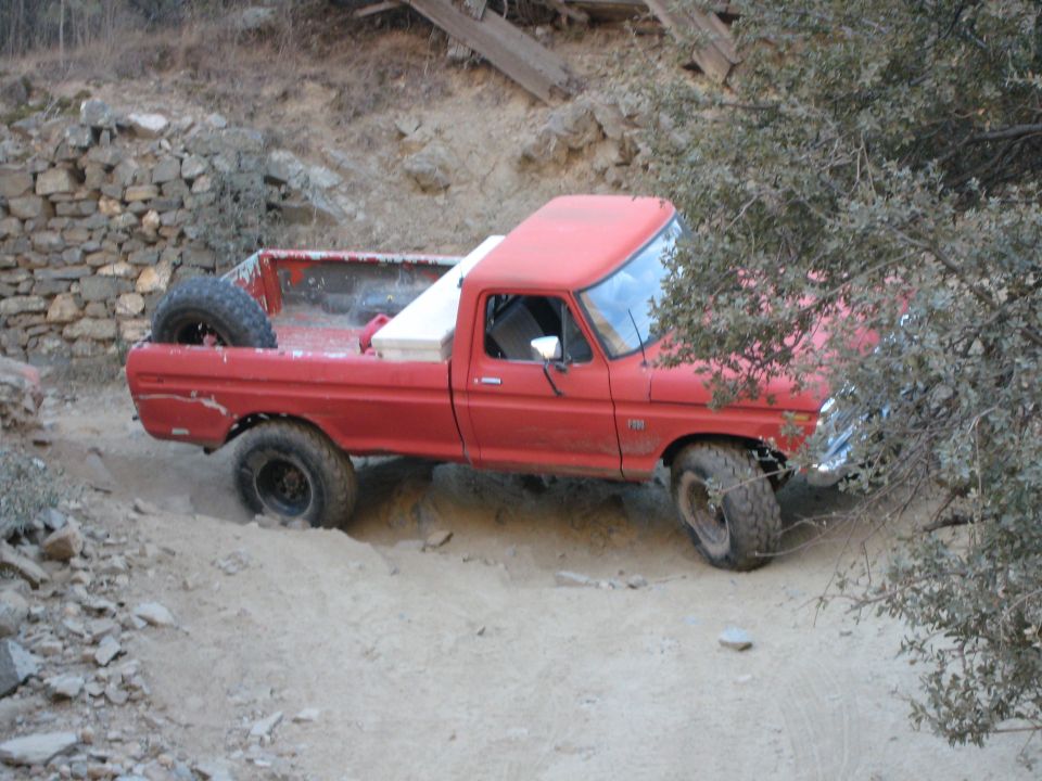 Red 1974 Ford F-250 off-roading on a dirt path