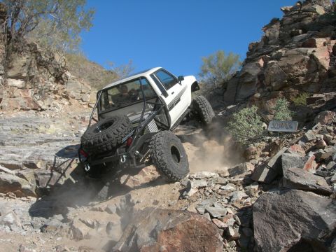 1974 Ford F-250 - This heavily modified truck navigates a challenging rocky incline, demonstrating its off-road capabilities.
