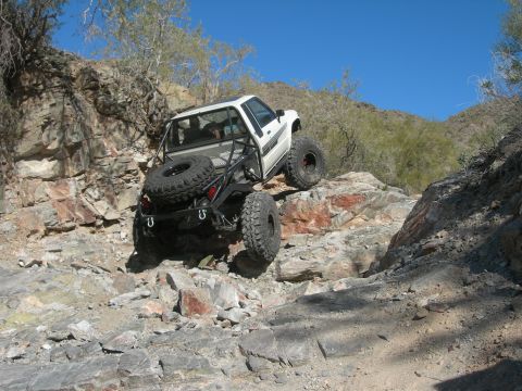 1974 Ford F-250 - Modified pickup truck with large tires and roll cage navigating a rocky trail.