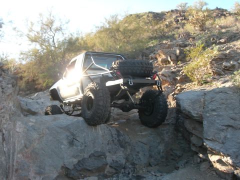 1974 Ford F-250 - A heavily modified off-road vehicle navigates a rocky, desert terrain.