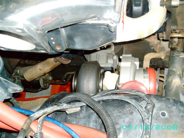 Turbocharger with red and orange piping, engine components, and wiring