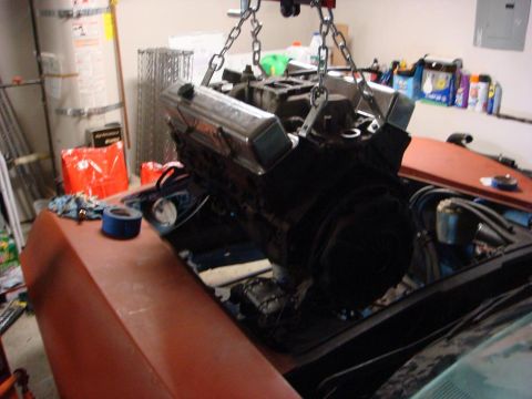 1975 Chevrolet Corvette - Engine being installed into a car's engine bay with an engine hoist.
