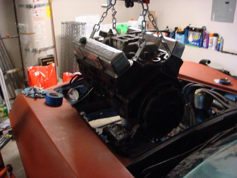 Engine suspended by chains over the engine bay of a car