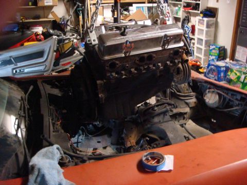 1975 Chevrolet Corvette - An engine is suspended by chains and being installed into the engine bay of a car.