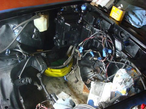 1975 Chevrolet Corvette - The engine bay is being prepped for work, with exposed wiring and some parts removed for restoration.