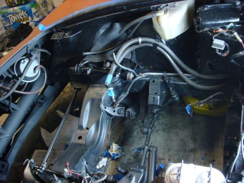 1975 Chevrolet Corvette - The engine bay of a vehicle undergoing work, showing various hoses and suspension parts.
