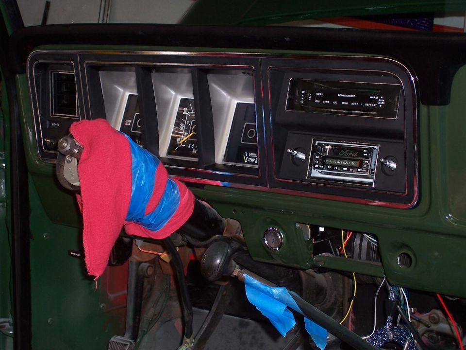 Dashboard with gauges, radio, and steering column covered in red cloth and blue tape