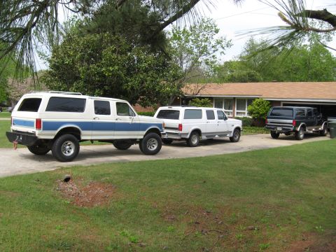 1995 Ford C-350 (Centurion Conversions) - A white and blue extended SUV is parked in a driveway next to two other SUVs.