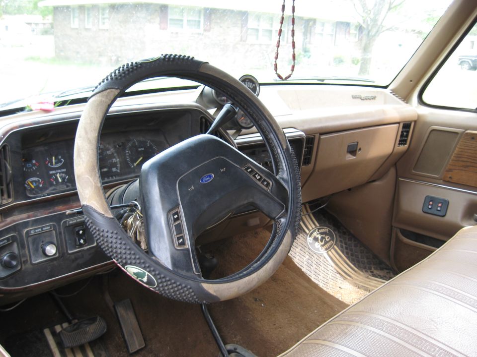 Interior view of a truck dashboard with a Ford steering wheel and tan upholstery