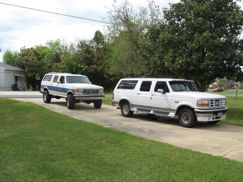 1995 Ford C-350 (Centurion Conversions) - Two Ford Centurion Conversions SUVs are parked in a driveway, one white and one white with blue trim.