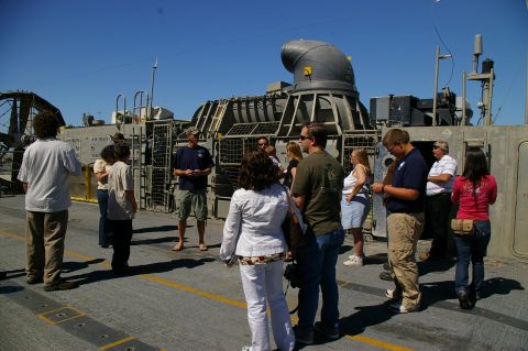 1986 Ford Bronco - A group of people observe a large hovercraft on a sunny day.