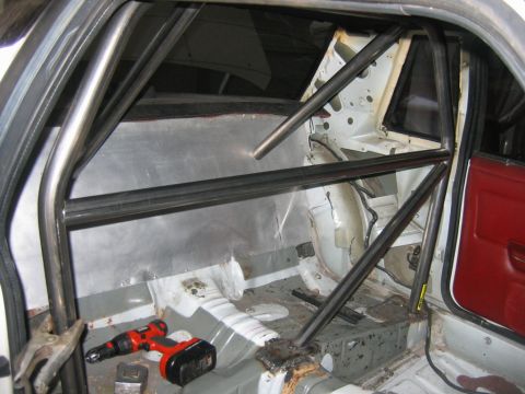 1992 Ford Mustang - The interior of a car is being modified with a roll cage, with a drill visible on the floor.