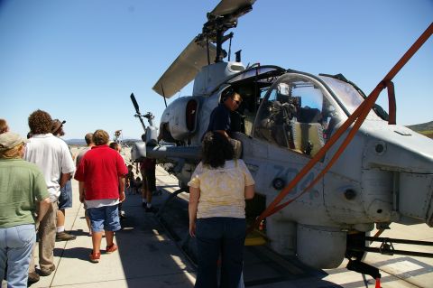 1986 Ford Bronco - A group of people observe a military helicopter on a sunny day.