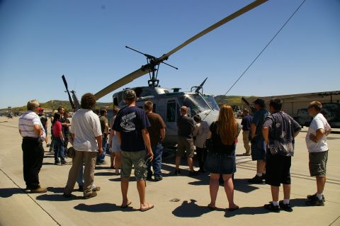 1986 Ford Bronco - Onlookers observe a helicopter parked on an airfield under a clear blue sky.