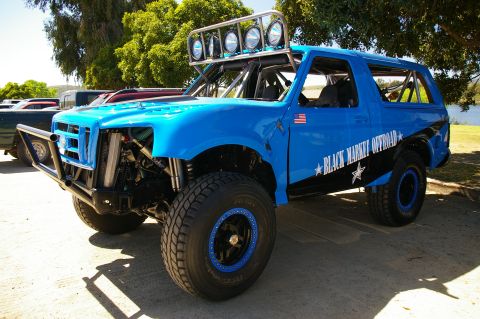 1986 Ford Bronco - A heavily modified blue SUV with off-road tires and a prominent light bar sits parked outdoors.