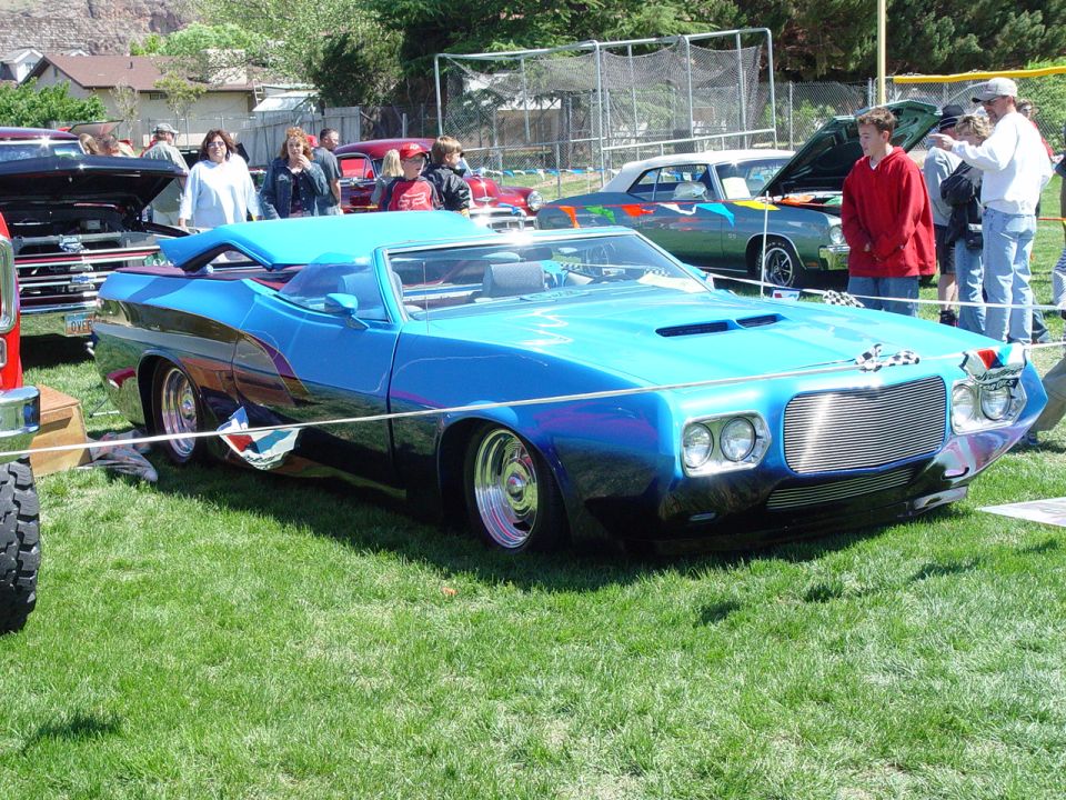 Heavily customized blue convertible show car with billet grille at a car show