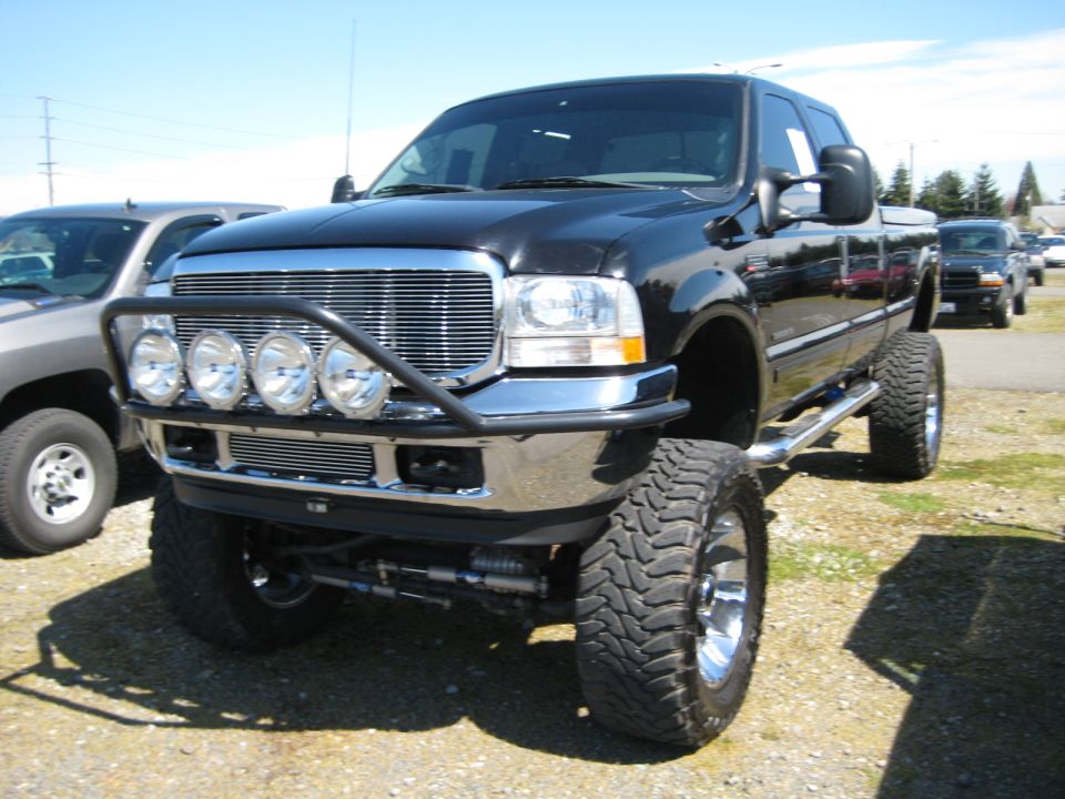 Black lifted pickup truck with chrome grille, bull bar, and four auxiliary lights