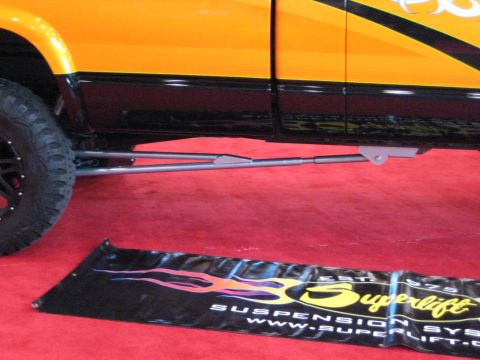1980 Ford Bronco - A custom suspension system is visible beneath a lifted pickup truck with flame graphics.