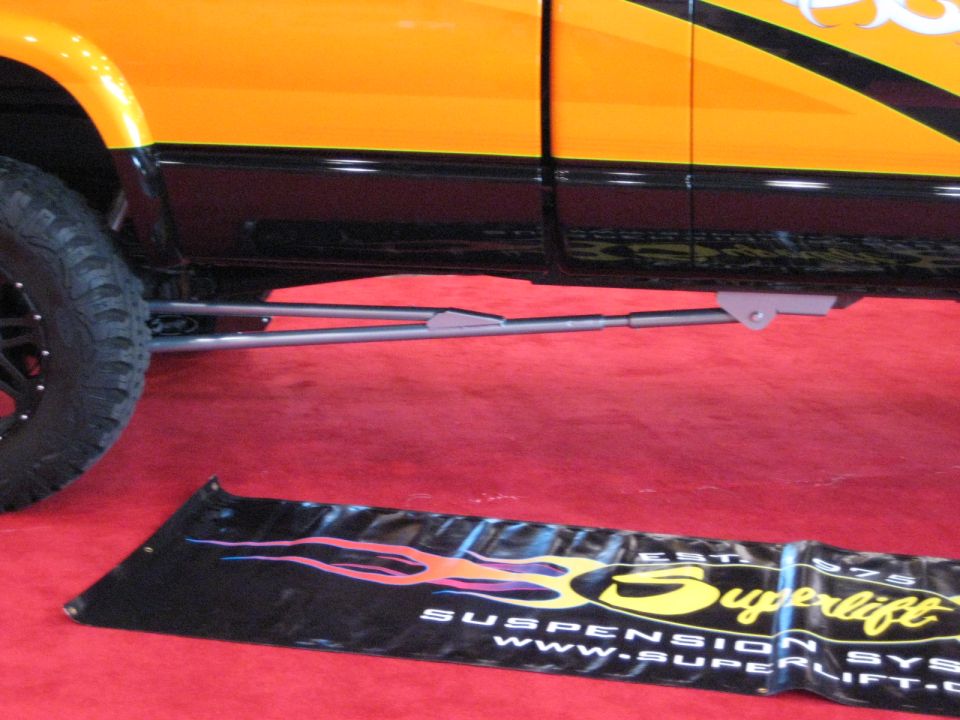 side view of a lifted pickup truck with custom suspension components and orange and black paint