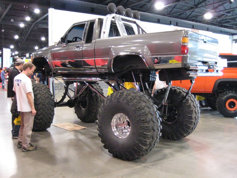 Gray lifted pickup truck with large tires and chrome trim, viewed from the front-right