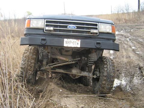 1990 Ford Bronco - Front view of a 1990 Ford Bronco navigating a muddy off-road path.