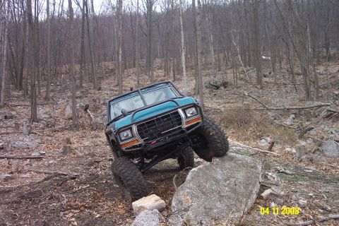 1992 Ford Bronco - Teal off-road SUV navigates a rocky trail, appearing to be from the 1978 model year.
