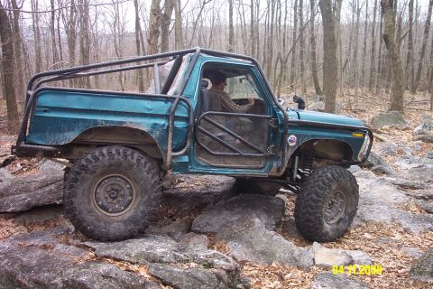 1992 Ford Bronco - This heavily modified SUV navigates rocky terrain, its custom roll cage and off-road tires evident.