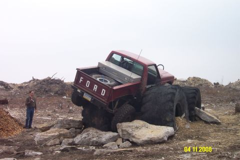 1992 Ford Bronco - A modified Ford pickup truck is stuck on rocks, with a person observing the situation.