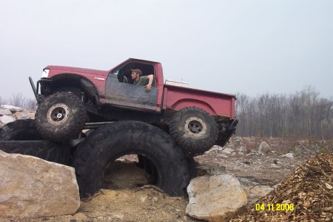1992 Ford Bronco - Modified red pickup truck navigating an obstacle course of rocks and tires.