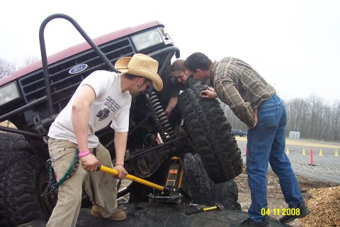 1992 Ford Bronco - Mechanics work on the front end of a lifted 1992 Ford Bronco during an off-road event.