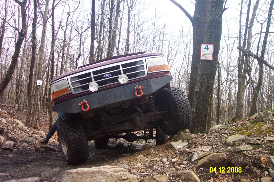 Maroon 1992 Ford Bronco front grille and bumper on rocky terrain