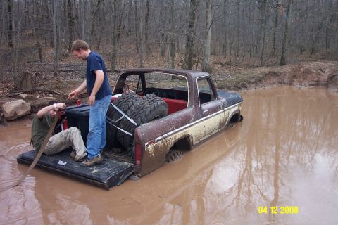 1992 Ford Bronco - Two people attempt to free a Ford truck that is stuck deep in a muddy pit.