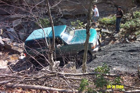 1992 Ford Bronco - A green 1992 Ford Bronco is seen off-roading on a rocky, wooded trail.
