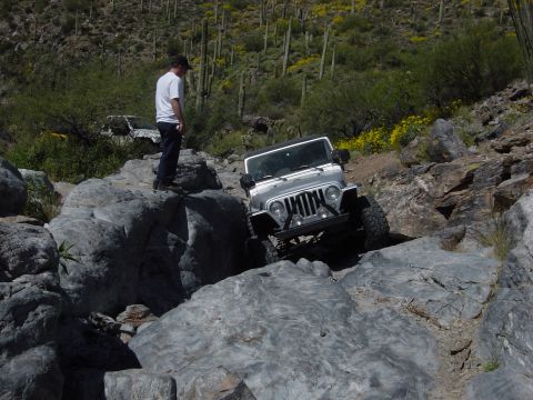 2004 Jeep Wrangler - A silver 2004 Jeep Wrangler navigates a challenging rocky terrain, with another vehicle visible in the background.