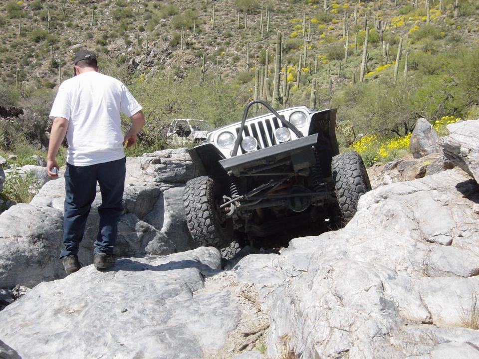 2004 Jeep Wrangler navigating a rocky trail, front-right tire angled up