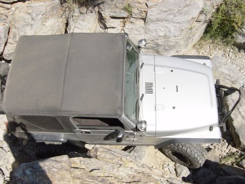 2004 Jeep Wrangler - A silver Jeep Wrangler with a soft top is shown from a high angle, traversing a rocky, off-road path.