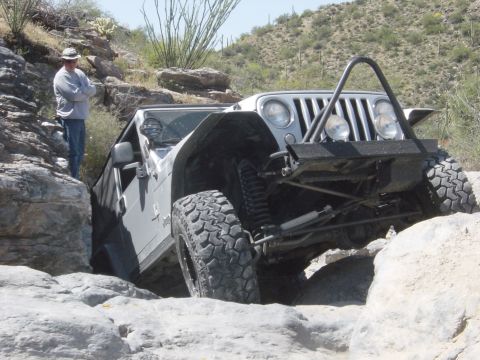 2004 Jeep Wrangler - A Jeep Wrangler tackles a challenging rocky terrain with a person observing the action.