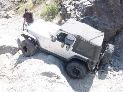 2004 Jeep Wrangler - A Jeep Wrangler navigates a challenging rocky terrain, with a person standing nearby observing.