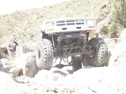2004 Jeep Wrangler - A heavily modified off-road vehicle navigates a rocky desert terrain, its extreme suspension and tire capabilities.