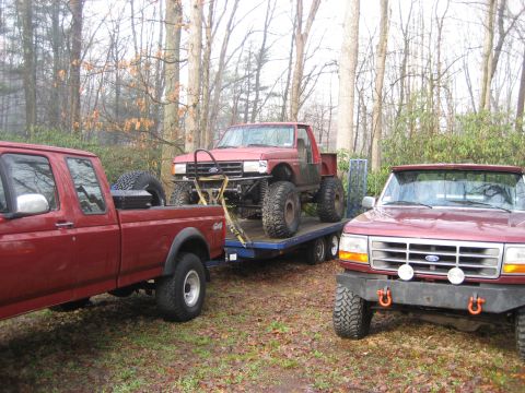1991 Ford Bronco - A 1992 Ford F-150 is parked in front of a trailer carrying another modified Ford truck.