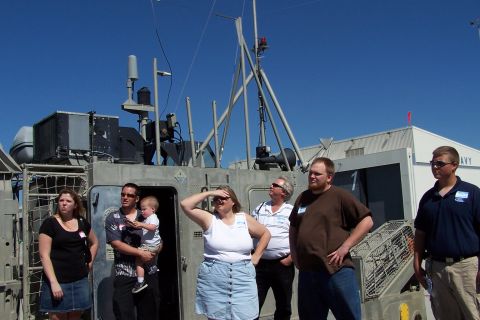 1990 Ford Bronco - Several individuals observe a military vessel docked outdoors on a sunny day.