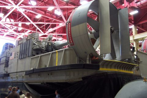 1990 Ford Bronco - A large US Navy hovercraft is shown inside a building with a red truss ceiling.
