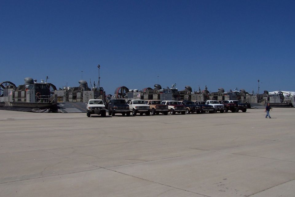 White 1990 Ford Bronco parked in a line with other SUVs in front of hovercraft